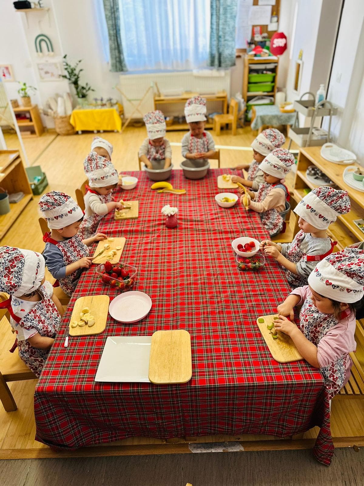 Fetiță în halat verde de pictură, văzută din profil, lucrând la șevalet, la grădinița Montessori Land